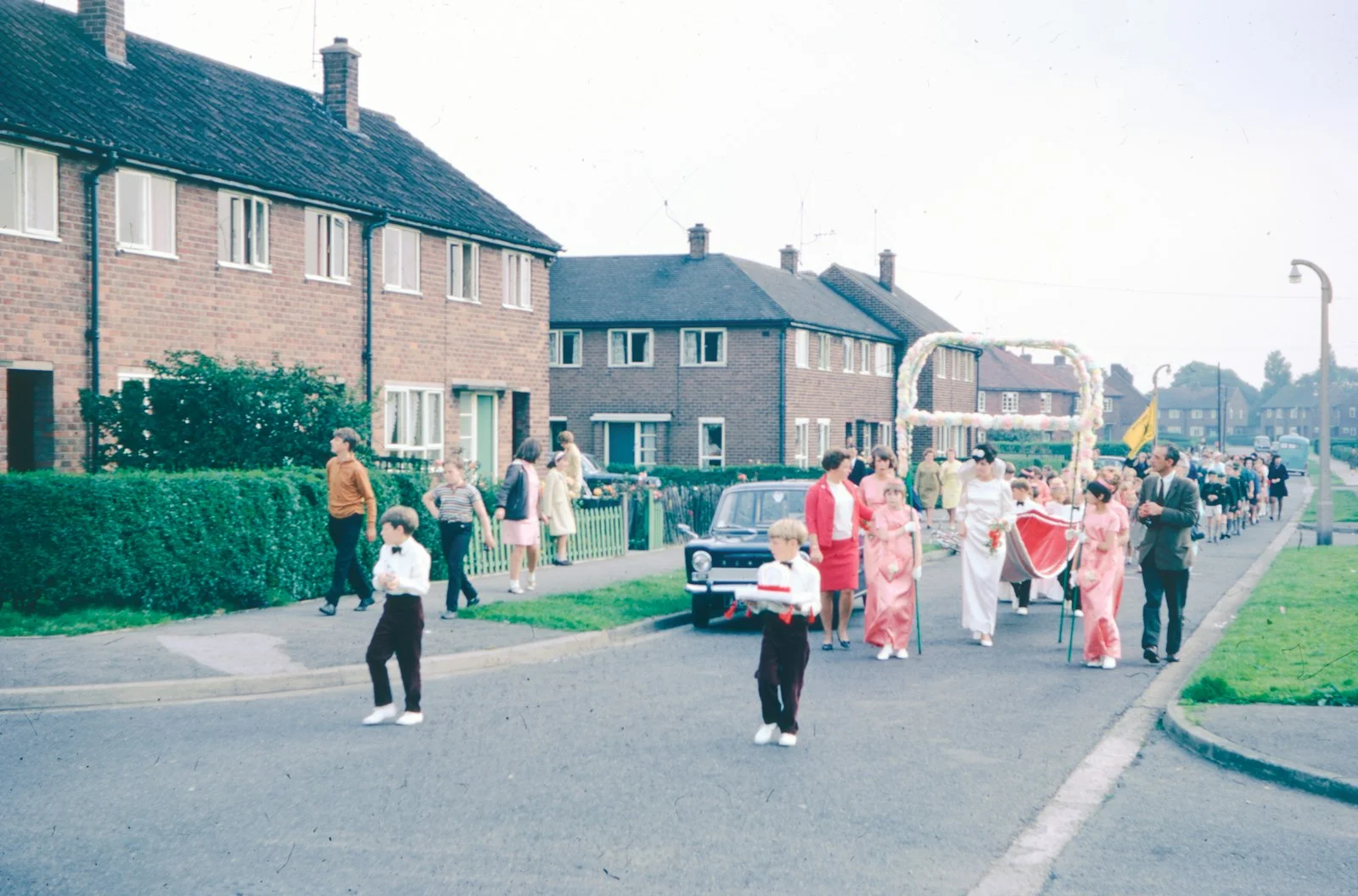 People parade down a street, dressed in white clothing