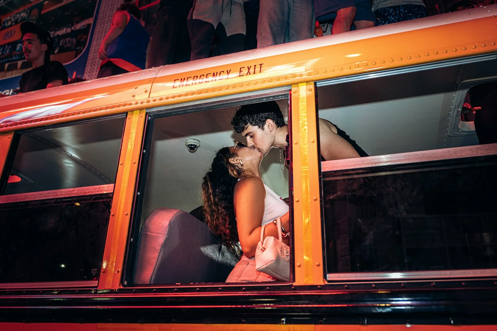 A couple kissing inside an orange bus at night
