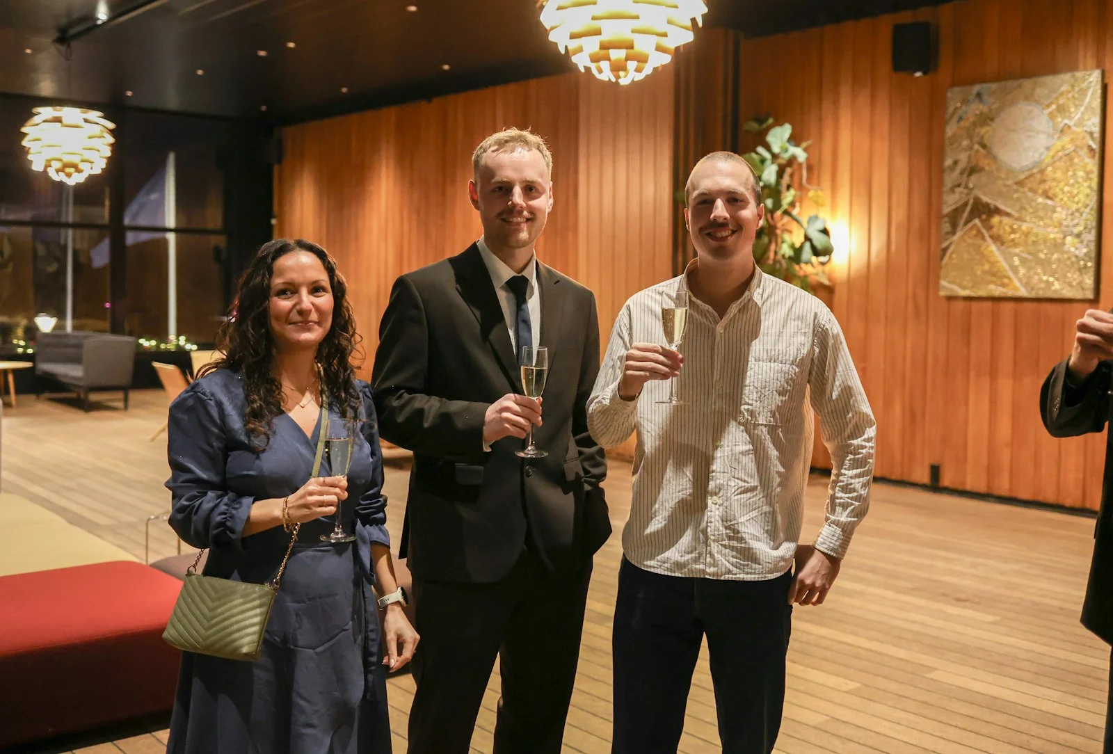 Three people holding champagne glasses at an event Three people holding champagne glasses at an event